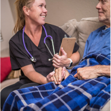 A medical professional wearing a stethoscope holds a patient's hand
