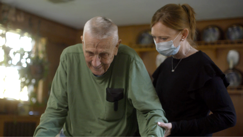 A caregiver holding an older woman's hand in both of hers